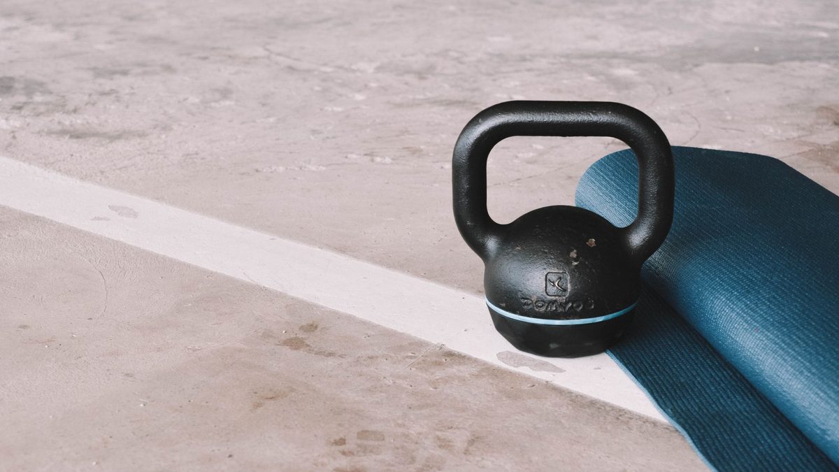 Kettlebell posée près d'un tapis roulé dans un intérieur clair