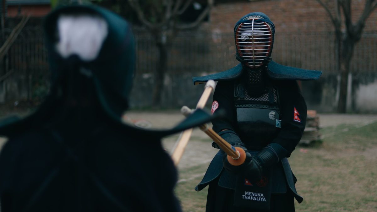 Deux kendoka en armure se font face, shinai levé, en extérieur