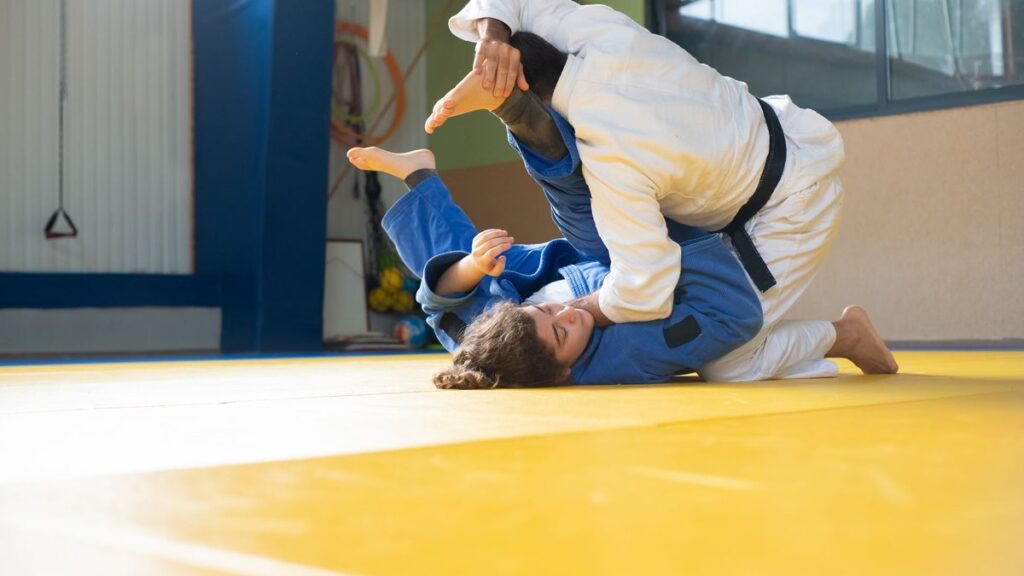Deux judokas au sol pendant un combat sur tatami jaune
