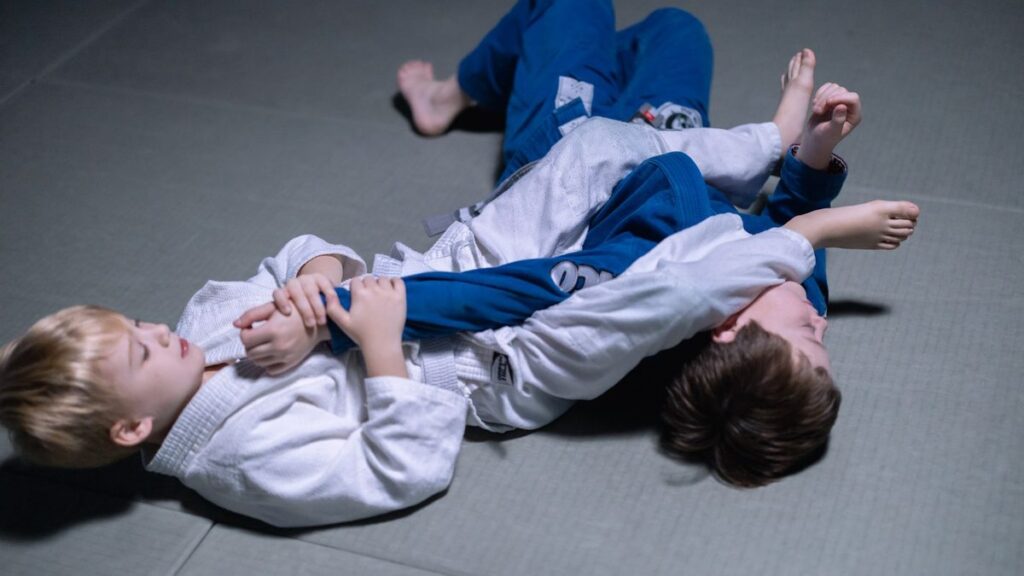 Jeunes pratiquants en veste de judo blanche et bleue au sol