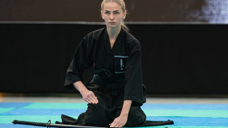Pratiquant en tenue noire dégainant un sabre japonais lors d'un kata